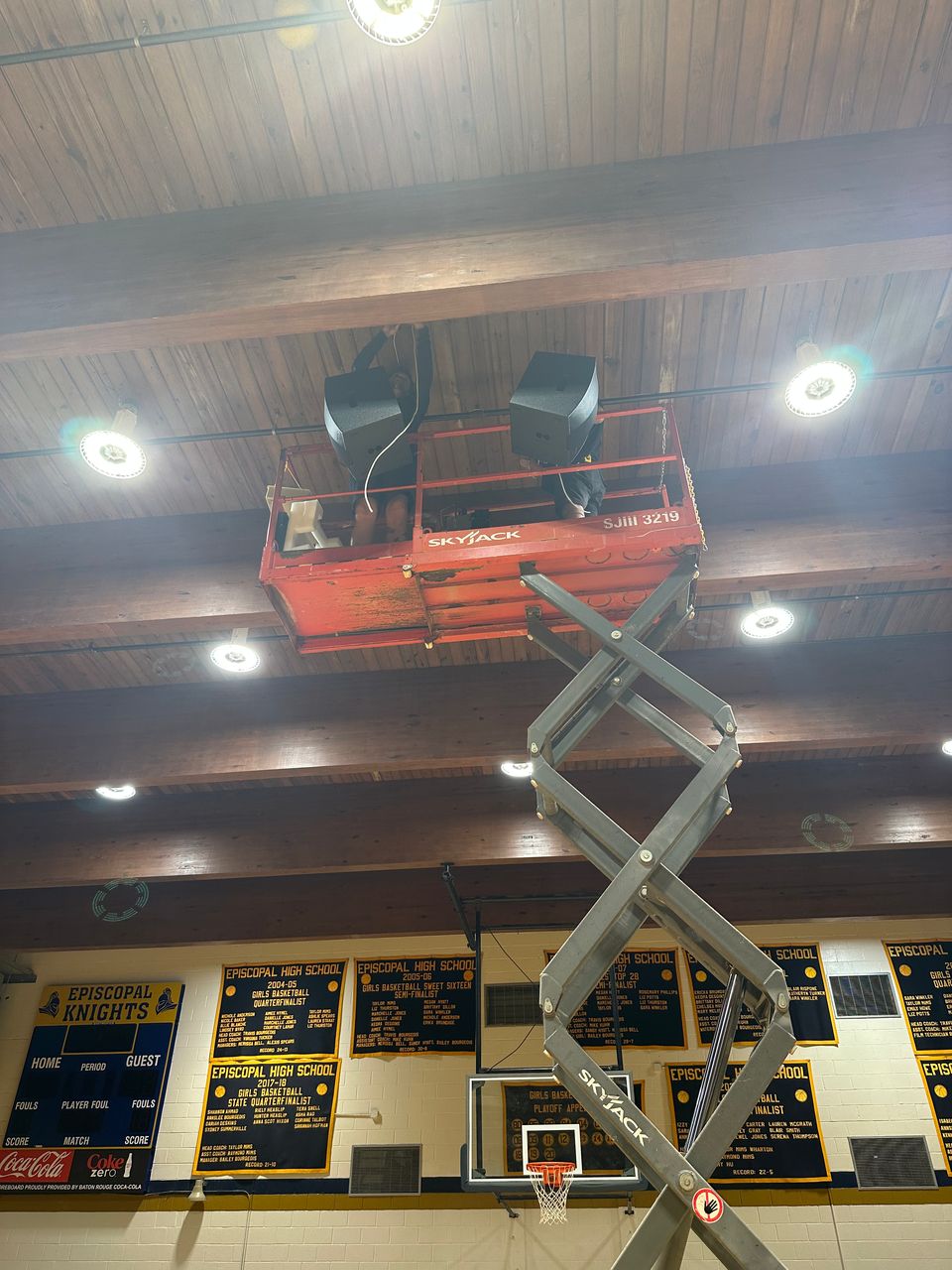 Tight detail of two Blaze loudspeakers hung between dark wood ceiling beams, with cabling routed cleanly along the beam line.