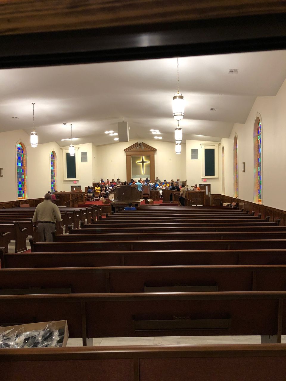 Rebuilt Greater Mount Olive sanctuary, stained glass arches, illuminated cross, choir setup, and Worx Audio loudspeakers hung from the ceiling.